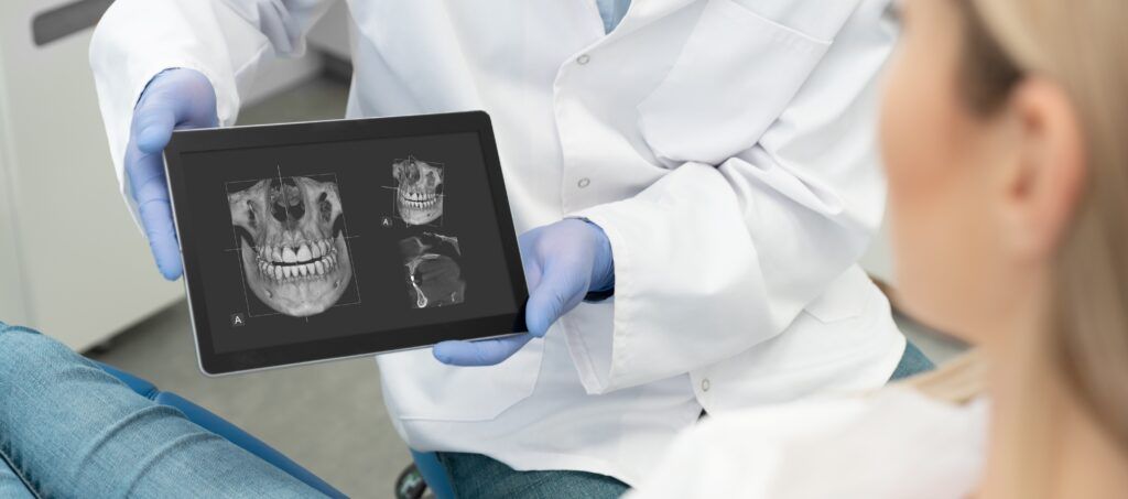 Dentist showing a patient 3D implant planning scans on a tablet during a consultation